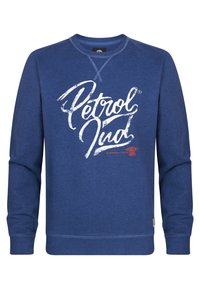 Sudadera azul de tejido suave, con un gran logotipo gráfico blanco que dice "Petrol Ind" en el frente. Diseño de manga larga y cuello redondo.
