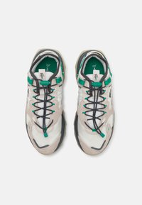 Lightweight sneakers with a beige and white upper, green accents, black laces, and a textured rubber sole. Features a cushioned collar and tongue.