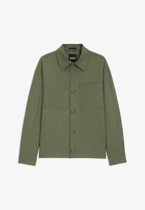 Olijfgroene jas van een gestructureerde stof, met een gespreid kraag, twee borstzakken en knoopsluiting aan de voorkant.