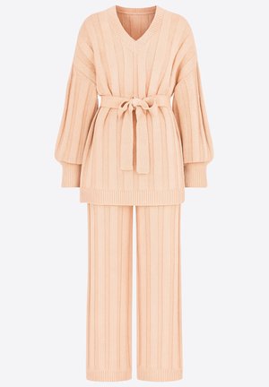 Dres dzianinowy w miękkim brzoskwiniowym kolorze, składający się z góry z dekoltem V o prążkowanej fakturze i szerokich rękawach, taliowany paskiem w tym samym kolorze.