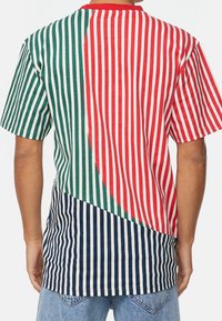 Camisa de manga corta a rayas multicolores con secciones en verde, rojo y azul marino, con rayas horizontales y verticales, de material de algodón.