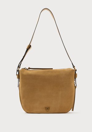 Sac à bandoulière en suède beige avec une bandoulière ajustable, une fermeture éclair sur le dessus, des zips sur les côtés et un petit logo métallique au centre devant.