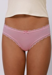 Pink lace-trimmed panties featuring sheer mesh fabric, a low-rise cut, and a small bow accent at the center front. Soft texture.