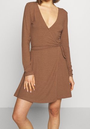 Brown ribbed long-sleeve wrap dress with a deep V-neck, cinched waist tie, and flared skirt, featuring textured fabric and subtle stretch.