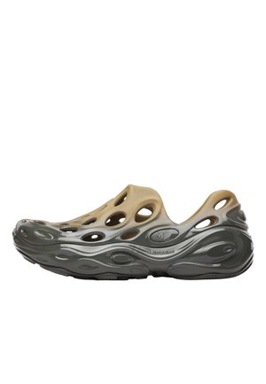 Scarpa slip-on marrone chiaro e nera con molte grandi aperture di ventilazione e suola ondulata e strutturata.