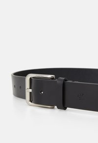 Black leather belt with a silver metal buckle, featuring holes for adjustment and engraved branding on the leather.