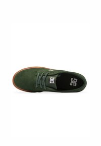 Grön mockasneaker med rund tå, gummisula och matchande snören. Har en logotypapplikation på tungan och ett strukturerat mönster på sulan.