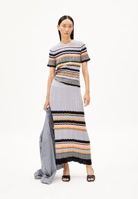 Ein gestricktes Zweiteiler-Outfit, bestehend aus einem kurzärmligen Oberteil und einem langen Rock mit mehrfarbigen horizontalen Streifen in Grau, Schwarz, Orange und Gelb.