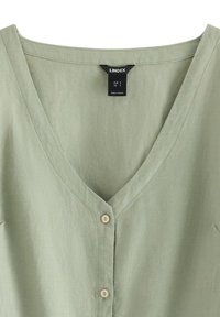 Linned blouse i dæmpet grøn med en dyb V-halsudskæring, med fem kremfarvede knapper på forsiden til lukning.