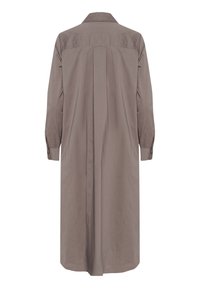 Rudas, ilgomis rankovėmis marškinėlių suknelė, pagaminta iš lygios medžiagos. Turi klasikinį apykaklę, mygtukinius rankogalius ir centrinę siūlę nugaroje.