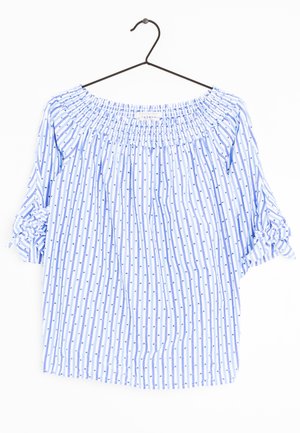 Lyseblå off-shoulder bluse med vertikale striber og små prikker, trekvartlange ærmer bundet i sløjfer, hængende på sort bøjle.