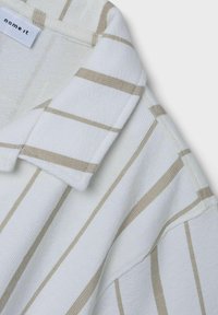 Biela košeľa s béžovými vertikálnymi pruhmi, s textúrovanou látkou a klasickým golierom. Na štítku je nápis "name it." Akcenty sú minimalistické.