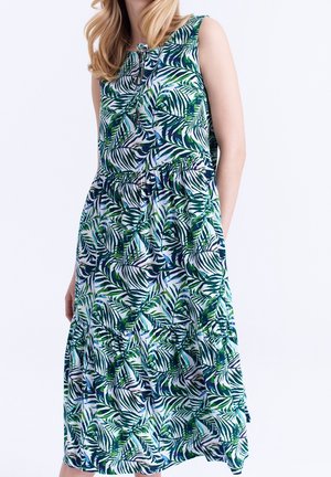 Ärmelloses Midikleid mit grünem und blauem tropischem Blättermuster, geraffter Taille und Binddetail am Ausschnitt, getragen von einer stehenden Person.