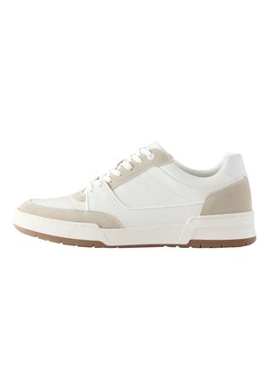 Zapatilla blanca de corte bajo con detalles en ante beige, cordones blancos, parte superior de cuero texturizado y suela de goma marrón sobre fondo blanco.