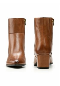 Brązowe skórzane botki sięgające kostki o gładkim wykończeniu, z niskim obcasem w kształcie bloku i bocznym zamkiem błyskawicznym. Design jest smukły i minimalistyczny, bez wzorów.