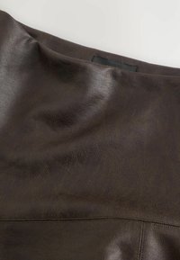Garbaccio in pelle marrone scuro che mostra texture e dettagli di cucitura su uno sfondo bianco.