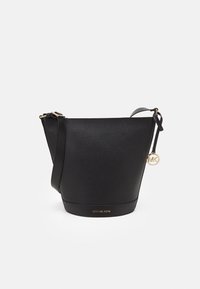 Borsa a secchiello nera in pelle con finitura testurizzata, hardware dorato, tracolla regolabile e charm logo pendente. Presenta una base piatta.