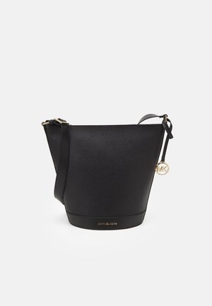 Black leather bucket bag with a textured finish, gold hardware, adjustable strap, and a hanging logo charm. Features a flat base.