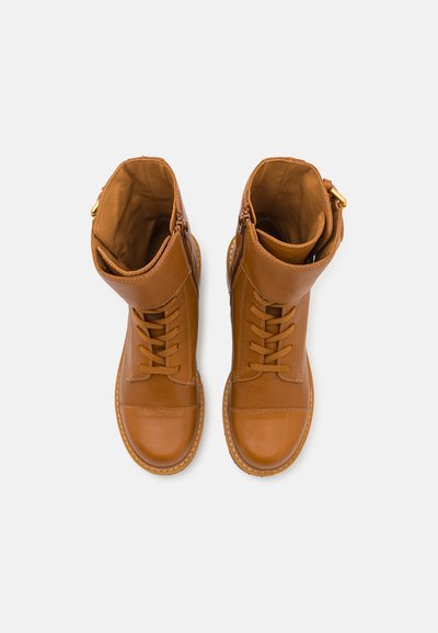 Brown leather ankle boots with lace-up front, padded collar, and side zippers. Smooth texture, rounded toe, and contrasting stitching detail.