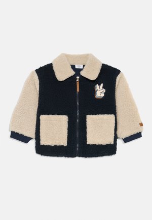 Fleece jacket with navy body and cream sleeves. Features a zip front, pointed collar, two front pockets, and a peace hand embroidered detail.