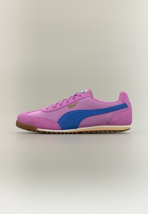 Lage roze sneaker met blauwe streep, bruine zool en gouden Puma-logo aan de zijkant, getoond in een linker zijaanzicht.