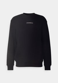 Musta collegepusero, valmistettu puuvillasekoitteesta, jossa resorit hihansuissa ja helmassa. Valkoinen "EMPORIO ARMANI" -logo keskellä rintaa. Pyöreä pääntie.