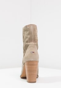 Botines de ante beige con patrón de corte, tacón alto apilado y costura decorativa. Presenta etiqueta de logo en el talón.