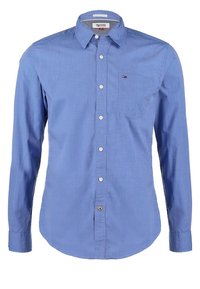 Chemise bleu clair à manches longues avec boutons, col, poche poitrine et petit logo Tommy Hilfiger sur la poche.