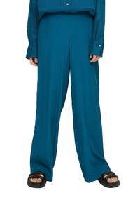 Turkosa, vida byxor i lätt tyg med hög midja och slät yta, matchade med svarta sandaler.