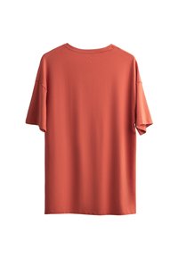T-shirt en coton doux à manches courtes et coupe oversize, en orange brûlé, avec un col rond et un subtil détail de couture au dos.