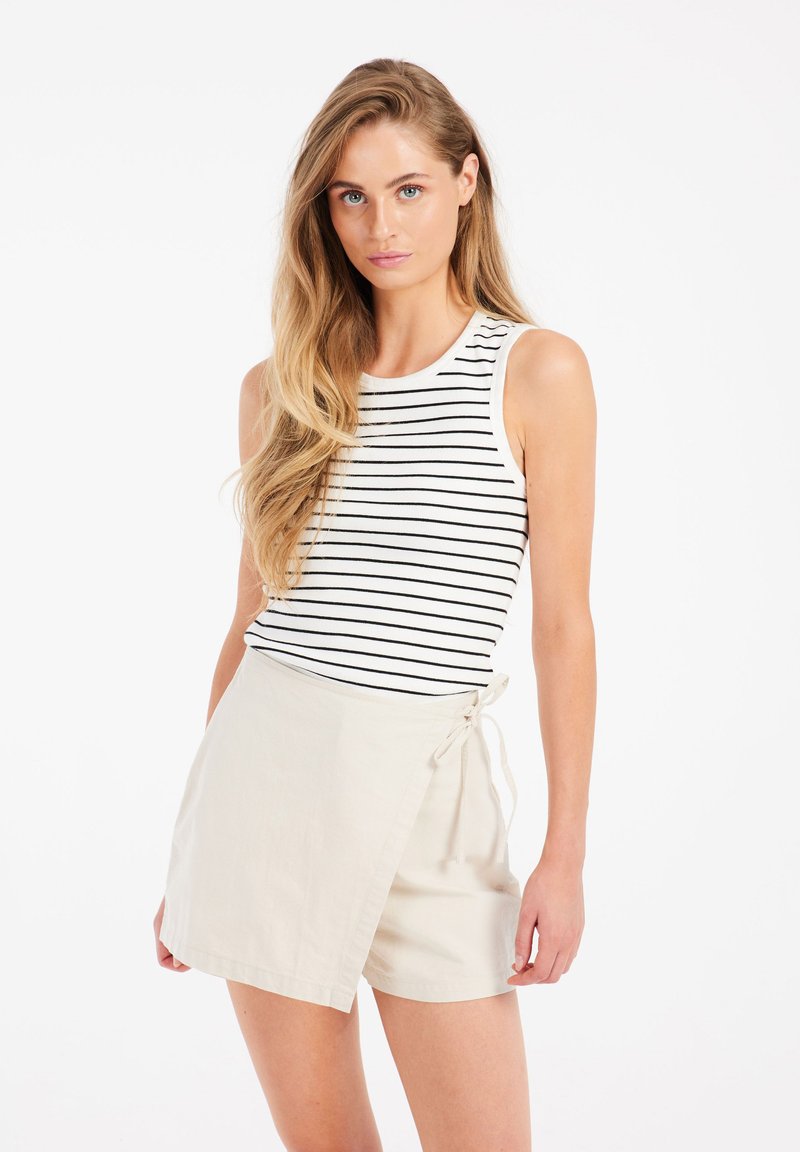 Striped tank top in white and black paired with a light beige wrap skirt, made from soft fabric with a tie closure on the side.