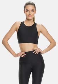 Sujeción deportiva negra con un escote alto y tirantes anchos, combinada con leggings negros de cintura alta, confeccionados con una tela suave y elástica.