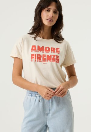 Cream-colored t-shirt with red "AMORE FIRENZE" text, rolled short sleeves, paired with light blue drawstring waist pants.