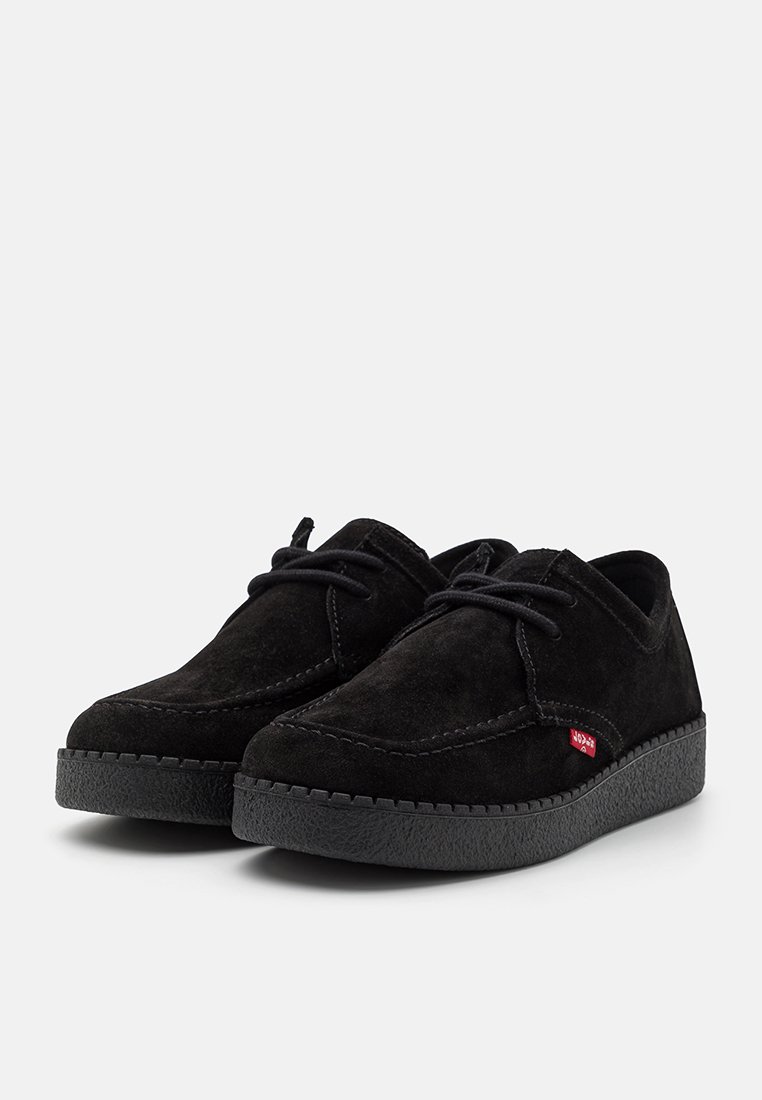 Chaussures en suede noir avec un bout arrondi, semelle plate en caoutchouc et coutures contrastantes. Présente des lacets noirs et un petit accent de logo rouge.