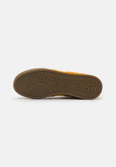 Rubber sneaker sole with zigzag tread pattern, brown color, featuring embossed brand logo and text. Flat profile, durable design for traction.