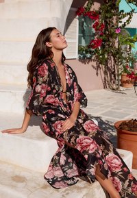 Svart kimono-klänning med blommönster i rosa och grönt, korta ärmar, djup V-ringning och volangdetaljer, som hänger ner till mitten av vaden.