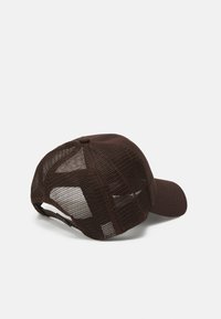 Brun trucker caps med solid frontpanel og mesh bak. Buet skygge og justerbar stropp for perfekt passform. Har en sentral knapp på toppen.
