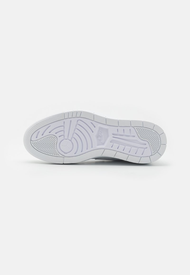 Semelle de sneaker Nike, en caoutchouc blanc avec des motifs texturés, des rainures circulaires et linéaires, et un logo embossed près du talon.