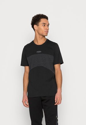 Zwarte t-shirt met korte mouwen en een grijze panel over de borst. Ronde halslijn, zachte katoen en een subtiele logodetail boven de borst.