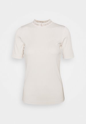 Haut à manches courtes côtelé couleur crème avec col montant orné du logo Calvin Klein Jeans beige autour du cou.