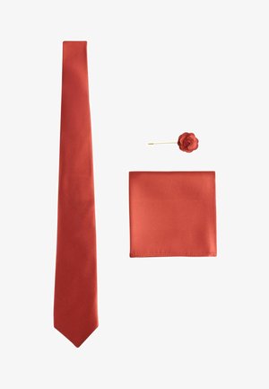 Krawatte aus seidenähnlichem Stoff in rostbrauner Farbe, passendes Einstecktuch und blumenförmige Anstecknadel mit goldenem Stiel auf weißem Hintergrund.