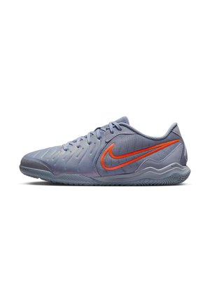 Chaussure de sport Nike grise basse avec dessus texturé et logo Nike swoosh orange sur le côté, présentée sur fond blanc.