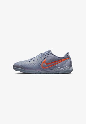 Chaussure de sport Nike grise basse avec dessus texturé et logo Nike swoosh orange sur le côté, présentée sur fond blanc.