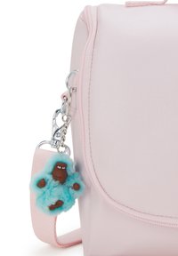 Borsa sintetica rosa con chiusura a pattina, dotata di un charm morbido color teal attaccato da un gancio in argento. La borsa presenta una texture liscia e bordi cuciti.