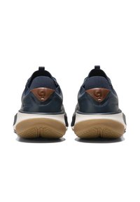 Marinblå sneakers med texturerat tyg och läderdetaljer. Gummisula med ett mönstrat grepp. Har en dragflik och en logotypdetalj på hälen.