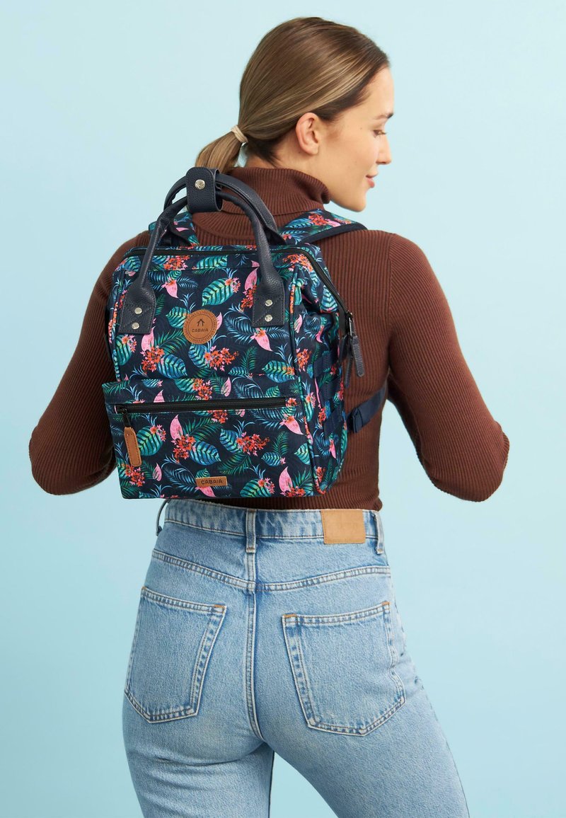 Floral-patterned backpack in dark navy with pink and green accents. Features dual carry handles, adjustable straps, and a front pocket.