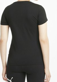 Camiseta negra ajustada de manga corta, con cuello redondo y textura de algodón suave. Sin patrones ni logos visibles en la parte posterior.