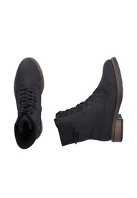 Bottines noires en cuir lisse, avec un laçage à l'avant, un panneau texturé sur le côté, et un talon en bloc en bois.