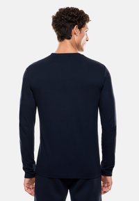 Maglietta a maniche lunghe blu navy realizzata in tessuto morbido, con scollatura rotonda e polsini aderenti, caratterizzata da un design semplice senza loghi visibili.