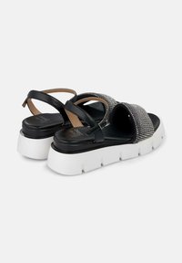 Sandali neri in pelle con una fascia accentuata in argento texturizzato, dotati di una suola bianca a piattaforma e un design a incrocio con una fibbia regolabile.